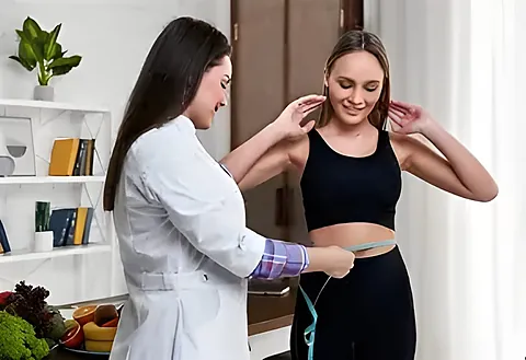 Médica midiendo la cintura de una paciente en consulta